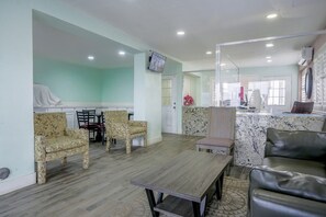 Habitación de hotel con comedor, televisor y baño con espejo y retrete.