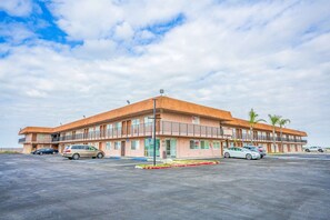 Un motel con techo plano, varios balcones y un estacionamiento con varios autos.