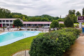 A pool area with a building in the background, a sign for Lloyds Country Inn, and a grassy area with a hedge. - Queen bed with Twin|Bryson city (Bryson city)