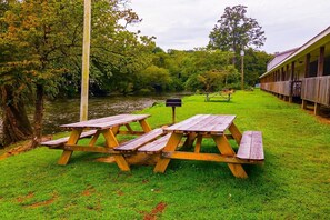 A riverside picnic area with wooden benches and a covered building. - Queen bed with Twin|Bryson city (Bryson city)
