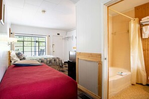 Quarto com cama, televisão, janela e chuveiro.