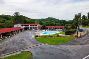 Um hotel com piscina, estacionamento coberto e vista para uma paisagem montanhosa.