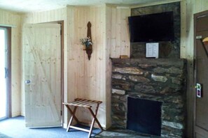 A room with wooden walls, a stone fireplace, a mounted television, and a door. - 2 Bedroom Apartment with Kitchen (Bryson city)