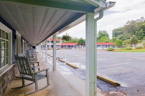 A covered outdoor seating area with chairs, a building with a red roof, and a parking lot. - 2 Bedroom Apartment with Kitchen (Bryson city)