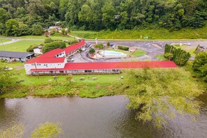 A building with a red roof, adjacent to a body of water, surrounded by greenery and a road. - 2 Bedroom Apartment with Kitchen (Bryson city)