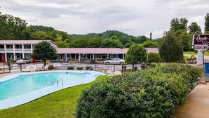 A pool area with a building in the background, a sign for Lloyds Country Inn, and a view of the surrounding greenery.