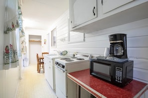 A kitchen with a stove, microwave, and coffee maker.
