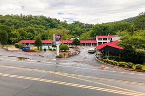 A hotel with red roofs, a sign for 'Country Inn,' and a parking lot with visible water puddles. - Queen Room - RiverFront (Bryson city)
