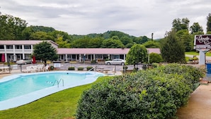 Zona de piscina con un edificio al fondo, un letrero que indica Lloyds Country Inn y vista de la vegetación circundante.