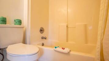 A bathroom with a white toilet, a bathtub, and a shower curtain.