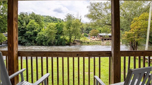 Une terrasse en bois avec des chaises, donnant sur une rivière et une végétation luxuriante.