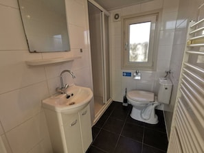 A bathroom with a sink, toilet, and a window.