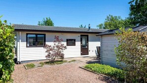 Uma casa móvel térrea com entrada de cascalho e um pequeno jardim.