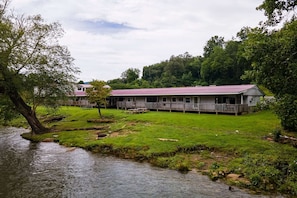 A riverside lodge with a wooden deck and a covered porch.