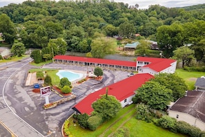 Um hotel com telhado vermelho, piscina e estacionamento.