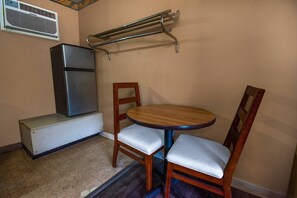 A compact kitchen with a refrigerator, a wooden dining table, and two chairs.