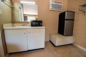A bathroom with a sink, mirror, microwave, refrigerator, and an air conditioning unit. - 2 Full Bed|Smoking|Calhoun GA (Calhoun GA)