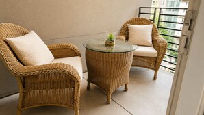 A balcony with wicker furniture, a glass table, and a small plant. - Calm & Stylish Hollywood Gateway (Los Angeles)