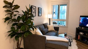 A living room with a grey sofa, a coffee table, a TV, a plant, and framed artwork on the wall. - Calm & Stylish Hollywood Gateway (Los Angeles)