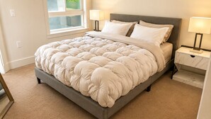 A neatly made bed with a tufted duvet, a grey headboard, and bedside lamps. - Calm & Stylish Hollywood Gateway (Los Angeles)