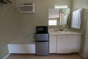 Un bagno compatto con un lavandino bianco, uno specchio, un asciugamano appeso al muro e un piccolo frigorifero.