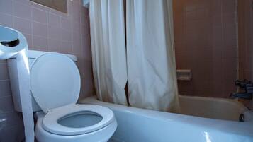 A bathroom with a toilet, a bathtub, and a shower curtain.