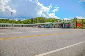 A motel with a green roof, a visible office, and a parking lot with several cars.