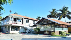 A two-story building with a covered entrance, a staircase, and a paved courtyard.