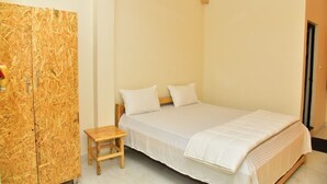 A bedroom with a bed, a small wooden stool, and a wooden wardrobe.