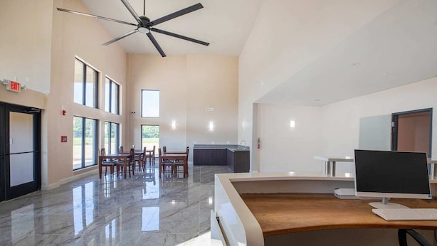 Un'ampia stanza con una scrivania grande, un ventilatore a soffitto e vista all'esterno attraverso ampie finestre.