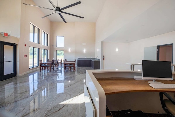 A spacious room with a large desk, a ceiling fan, and a view of the outdoors through large windows.
