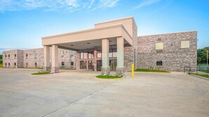 A modern building with a covered entrance, stone facade, and a spacious paved area in front. - 2 Queen Beds Non-Smoking (Adairsville GA)