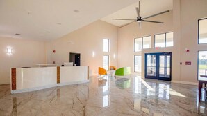 A spacious lobby with a reception desk, a ceiling fan, and large windows allowing natural light. - 2 Queen Beds Non-Smoking (Adairsville GA)