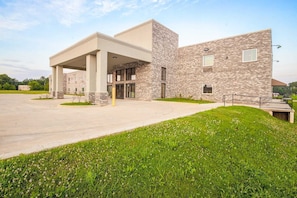 A modern building with a covered entrance, a paved driveway, and a grassy area.