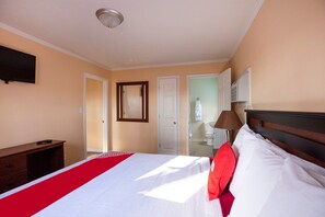 Ein Hotelzimmer mit einem Bett, einem Schreibtisch, einem Fernseher und einem durch eine offene Tür einsehbaren Badezimmer.