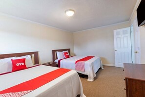 A hotel room with two beds, a TV, a door, and a dresser.