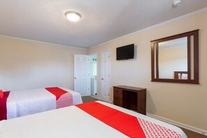Habitación de hotel con dos camas, un televisor, un espejo y un pequeño armario de madera.