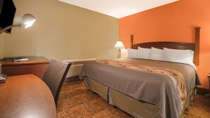 Ein Hotelzimmer mit Bett, Schreibtisch, Stuhl, Lampe und Heizung.