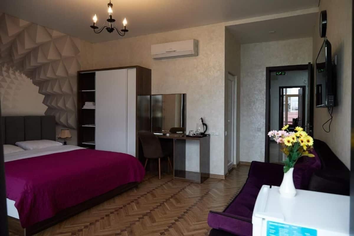 A hotel room with a bed, desk, chair, and a TV.