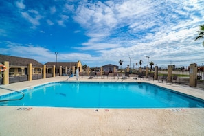 Une piscine avec des chaises longues et une clôture.