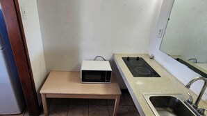 A compact kitchen with a refrigerator, a microwave on a small table, a gas stove, and a sink. - King Bed with Kitchenette Non-Smoking (Corpus Christi TX)