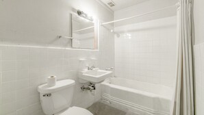 Une salle de bain comprenant des toilettes, un lavabo, un miroir et une baignoire.