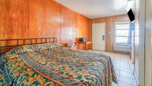 Une chambre à coucher avec un lit, des murs en bois, une petite table avec un téléviseur et une porte donnant sur un balcon.