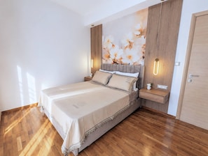 Ein Schlafzimmer mit einem großen Bett, Holzdielen, einer Wandleuchte und einer Tür.