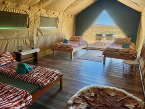 A tent with two beds, a small table, and a view of the desert. - Camp Gecko (Solitaire)