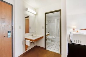 Une salle de bain dâhĂŽtel Ă©quipĂ©e dâun lavabo, dâun miroir, de toilettes, dâune douche et dâun tĂ©lĂ©viseur.