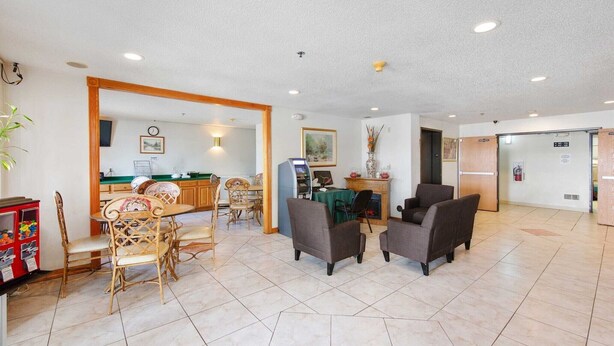 A hotel lobby with a dining area, a reception desk, and a seating area with chairs and a table.
