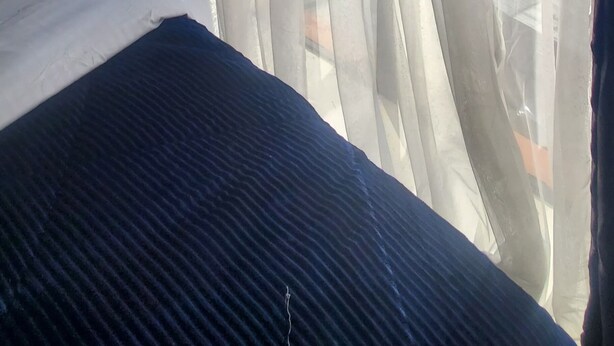 Una habitación con cama, cortinas traslúcidas y vistas a edificios.