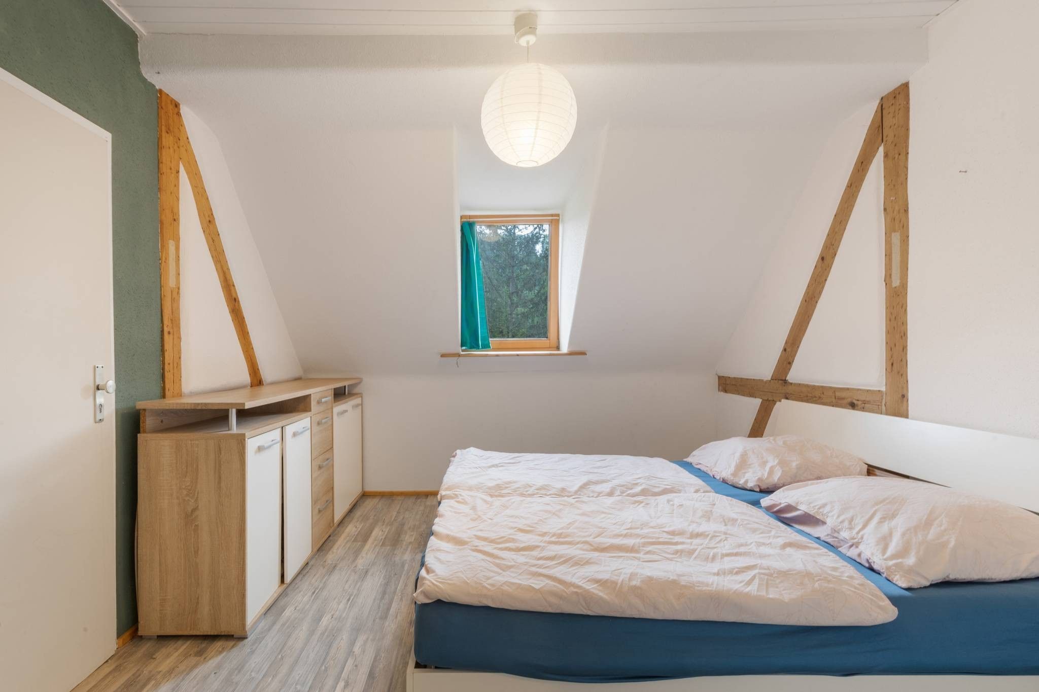 A bedroom with a bed, a window, and a desk.