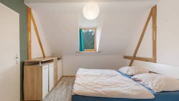 A bedroom with a bed, a window, and a desk.